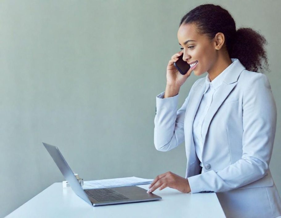 Frau im Business-Outfit Frau im Business-Outfit spricht am Telefon und nutzt einen Laptop.
