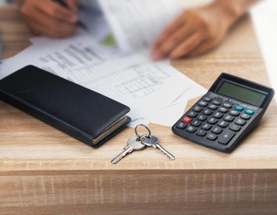 Ein Tisch mit einem Notizbuch, Schlüsseln, einem Taschenrechner und Dokumenten.